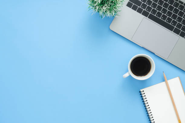 istock Minimal work space - Creative flat lay photo of workspace desk. Top view office desk with laptop, notebooks and coffee cup on blue color background. Top view with copy space, flat lay photography. 939184094