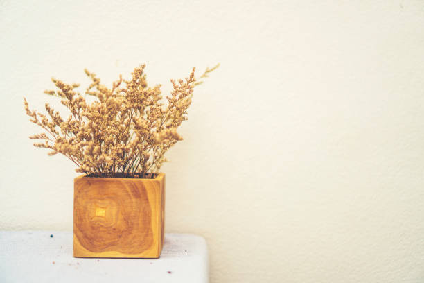 Small bouquet of colorful wildflowers in a handmade ceramic vase placed on a weathered wooden table. Natural light with soft focus background in green and yellow tones. Concept for countryside, springtime, simplicity, and rustic home decor.