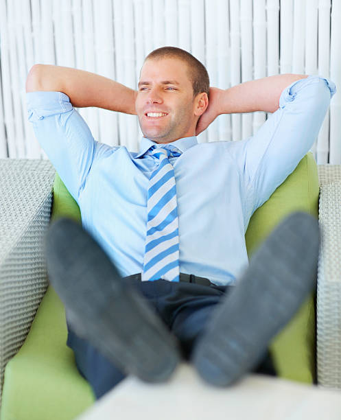 istock Smiling young businessman lying on couch 93919810