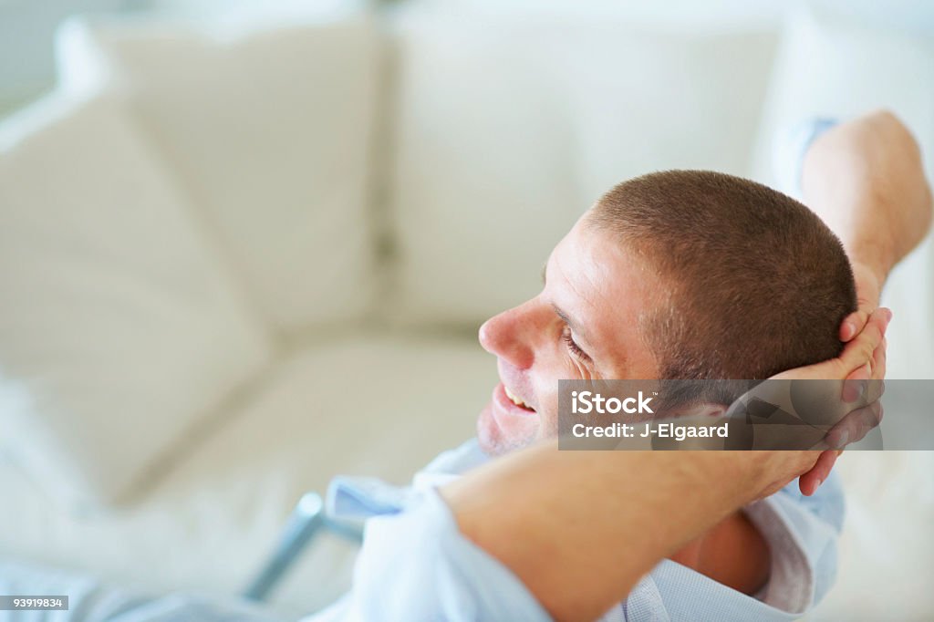 Ritratto di un sorridente giovane uomo rilassante a casa - Foto stock royalty-free di 20-24 anni