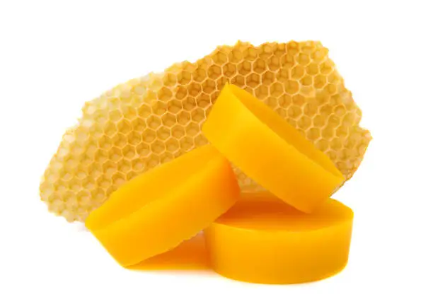 Photo of Yellow natural bee wax with a piece of honey cell on a white background.