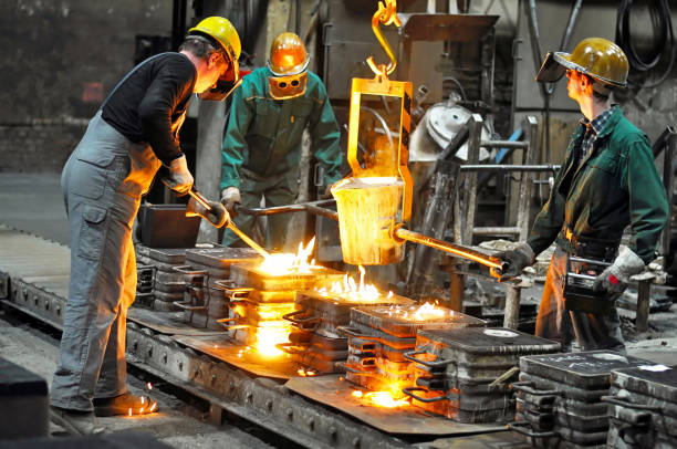 grupo de trabajadores de una fundición en el horno de fundición - producción de piezas de acero fundido en una empresa industrial - siderurgicas fotografías e imágenes de stock