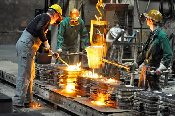 Photo of Group of workers in a foundry at the melting furnace - production of steel castings in an industrial company