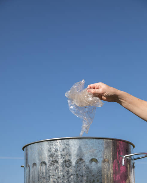 istock Hand places waste plastic into a dustbin an environmental challenge. 939206770