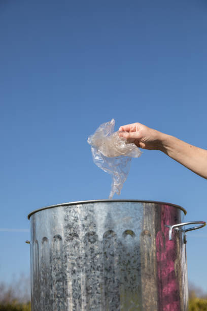 istock Hand places waste plastic into a dustbin an environmental challenge. 939207736