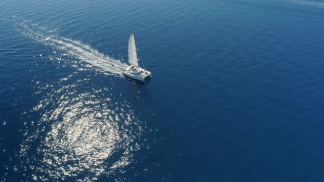 4K Aerial drone point of view catamaran on sunny blue ocean, real time
