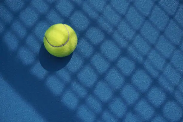 Tennis ball in the court with net shadow on it
