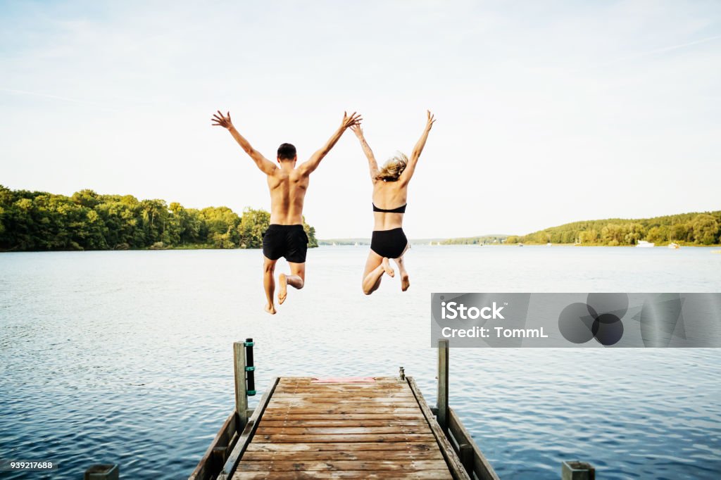 Deux amis sautant jetée au lac d’ensemble - Photo de Été libre de droits