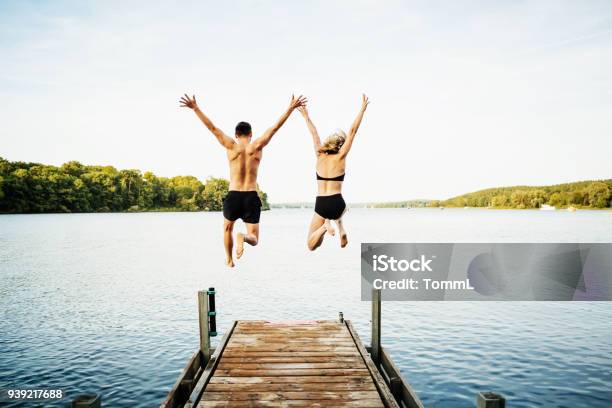 Photo libre de droit de Deux Amis Sautant Jetée Au Lac Densemble banque d'images et plus d'images libres de droit de Été - Été, Lac, Sauter