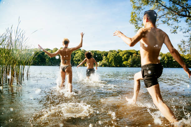 istock Group Of Friends Eagerly Running Into Lake Together 939217866
