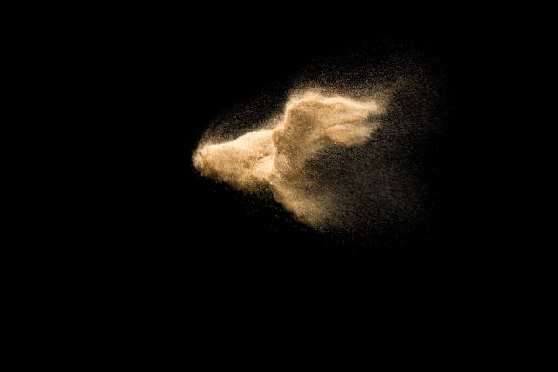 istock Abstract sand cloud. Golden colored sand splash agianst dark background. Yellow sand fly wave in the air. Sand explode on black background ,throwing freeze stop motion. 939238656