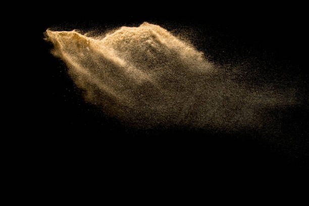 istock Abstract sand cloud. Golden colored sand splash agianst dark background. Yellow sand fly wave in the air. Sand explode on black background ,throwing freeze stop motion. 939238700