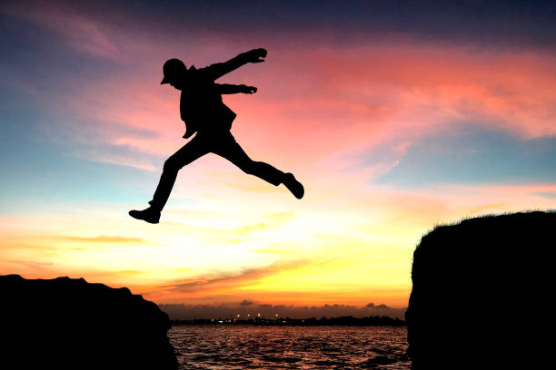 istock Silhouette of a man jumping over the cliff 939238858