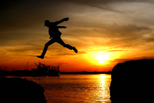 istock Silhouette of a man jumping over the cliff 939238930