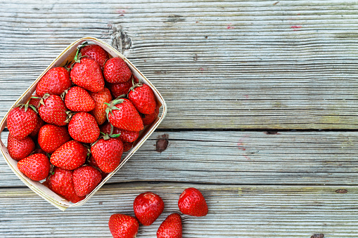 Ripe strawberries in a basket. Wild strawberry basket on wooden background