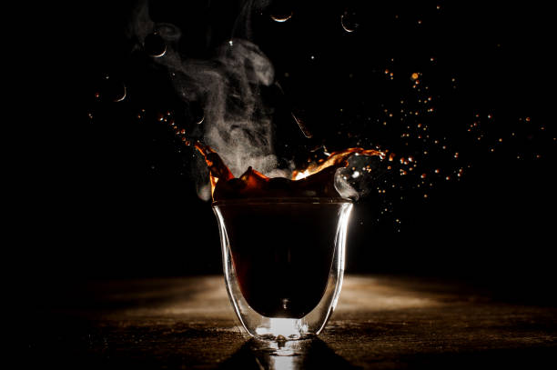 Splash of the coffee in the transparent glass on the dark background