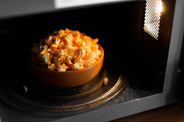 Big brown bowl of a delicious hot yellow popcorn standing right in the dark microwave