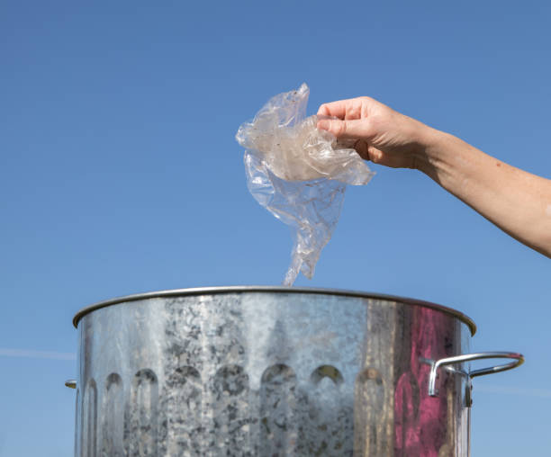 istock Hand places waste plastic into a dustbin an environmental challenge. 939248440