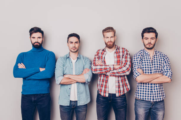 istock Ethnicity, multicultural diversity. Four serious harsh men are standing isolated on pure background with crossed hands, dressed in casual clothes and jeans 939254818