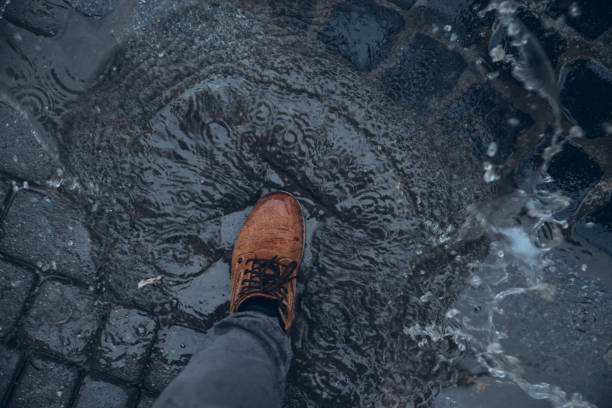 istock mans legs next to puddle. rainy weather. 939260896