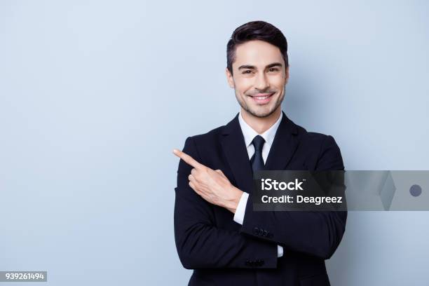 Photo libre de droit de Fermer Le Portrait De Guy Courtier En Bourse Jeunes De Brunete Réussie Sur Le Fond Bleu Clair Pur Il Est Souriant Portant Costume Avec Cravate Et Pointe Sur Une Surface Avec Son Doigt banque d'images et plus d'images libres de droit de Hommes