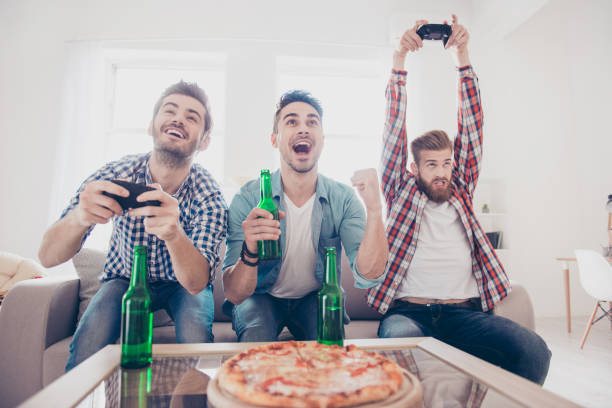 verrückt, spaß, freude, gewinner und verlierer! junge männer sind auf couch sitzen und spielen von videospielen drinnen zu hause mit bier und pizza, ausdruck von emotionen und gefühlen, gestik - winner looser stock-fotos und bilder