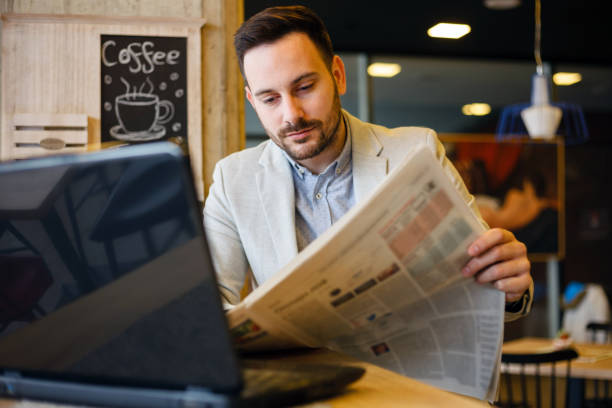 молодой бизнесмен-мужчина читает газеты в кафе - newspaper glasses the media reading стоковые фото и изображения