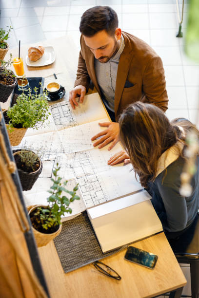 młodzi architekci płci męskiej i żeńskiej omawiający plany budowy w nowoczesnym biurze - architect women blueprint eyewear zdjęcia i obrazy z banku zdjęć