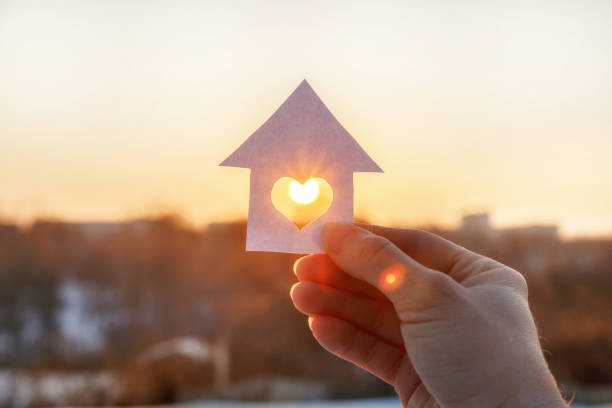 House of paper with a heart in the hand . House of paper with a heart in the hand on the rising sun background. peace sign gesture photos stock pictures, royalty-free photos & images