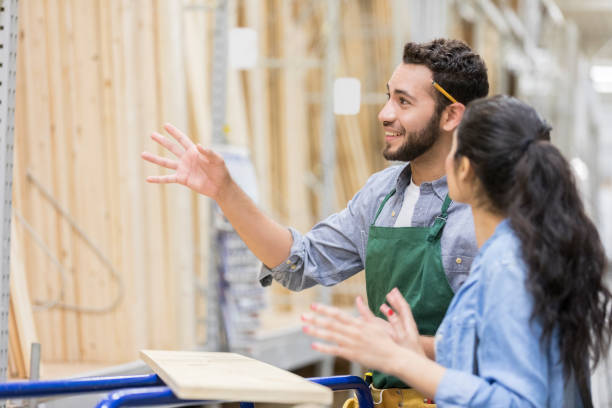 Hardware store employee assists customer Hardware store employee explains something to customer. He is gesturing while talking with a female customer. hardware store stock pictures, royalty-free photos & images