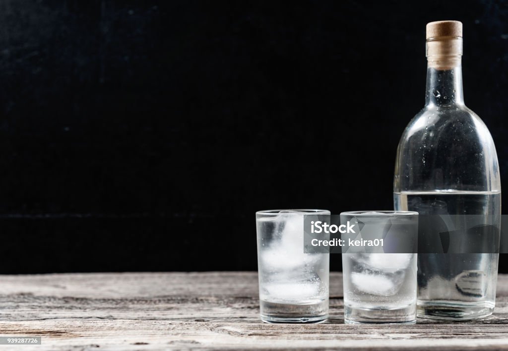 Cold vodka in shot glasses on a black background Cold vodka in shot glasses on a black background on wooden table closeup with copyspace Vodka Stock Photo