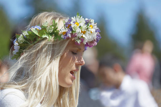 Blonde woman with flowers in her hair preparing to celebrate the Swedish Midsummer in Sweden VADDO, SWEDEN - JUNE 23, 2017: Blonde woman with flowers in her hair preparing to celebrate the Swedish Midsummer in Sweden, June 23, 2017 swedish woman stock pictures, royalty-free photos & images