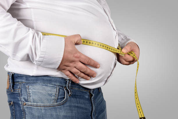 istock Overweight Man Measuring His Belly with tape measure 939290830