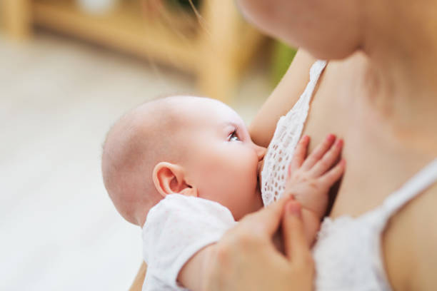 giovane mamma che allatta il suo bambino appena nato. concetto di lattante infantile. la madre nutre il figlio o la figlia con latte materno - succhiare foto e immagini stock