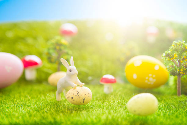 istock Happy Easter concept. Little Easter bunny toys and Easter eggs on green grass. Fairy tale sunset on the plastic green field with plastic grass, mushrooms and trees. Fake grass. Macro 939291206