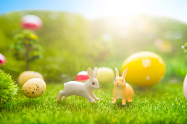 istock Happy Easter concept. Easter rabbits toy on spring green grass. Fairy tale sunset on the plastic green field with plastic grass, mushrooms and trees. Fake grass. Macro 939291350