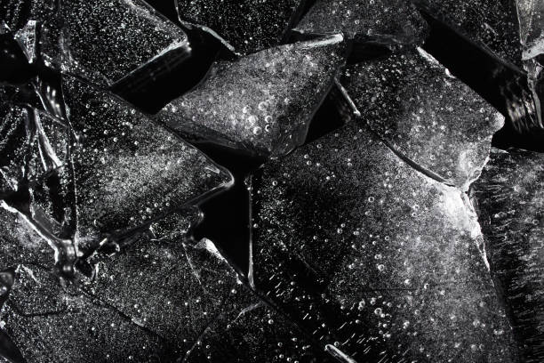Black ice texture. Photo texture of a black and white ice laying on dark background. black glass surface stock pictures, royalty-free photos & images