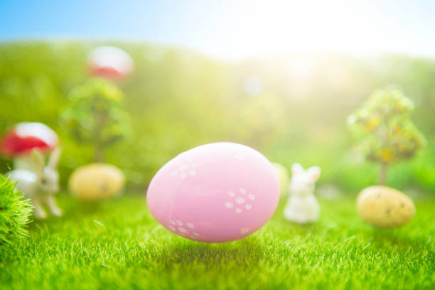 istock Happy Easter concept. Easter bunny and Easter eggs on green grass. Fairy tale sunset on the plastic green field with plastic grass, mushrooms and trees. Fake grass. Macro 939293438
