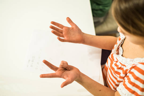 The girl counts on her fingers and writes on the table