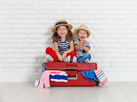 happy laughing children boy and girl with suitcase going on a trip