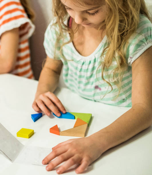 istock cute girl sitting at the table solving puzzle 939314496