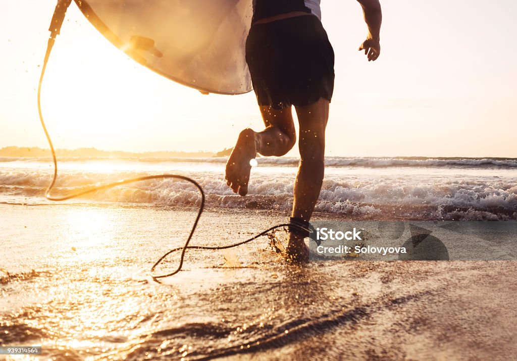 Man surfer run in ocean with surfboard. Active vacation, health lifestyle and sport concept image Surfing Stock Photo