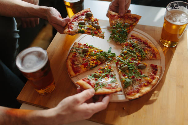 istock Friends hanging out, drinking beer and eating pizza 939325418