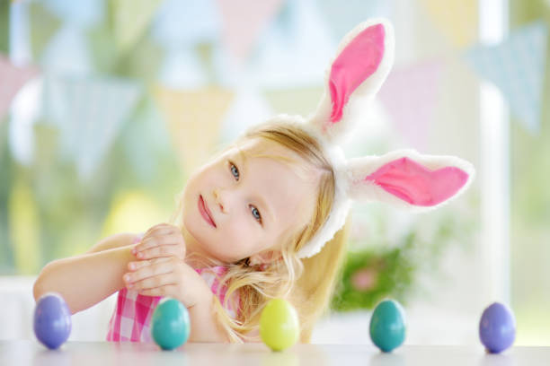 istock Cute little girl wearing bunny ears playing egg hunt on Easter 939325972