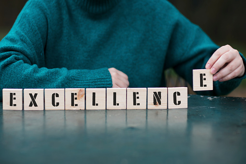 EXCELLENCE Concept ,Female hand playing with six wooden blocks