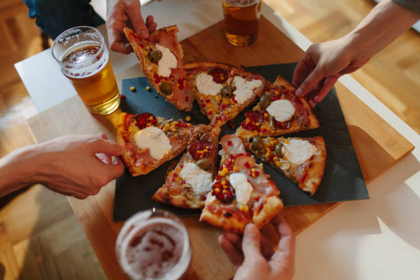 istock Friends hanging out, drinking beer and eating pizza 939326050