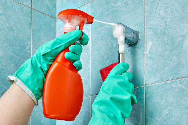 istock Hand in green glove holds cleaning agent with foam spray. 939328572