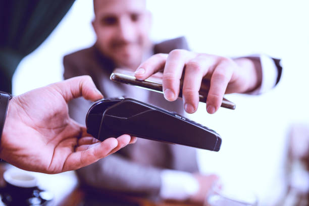 istock Smiling Businessman Paying Bill with Mobile Phone in a Restaurant 939337654