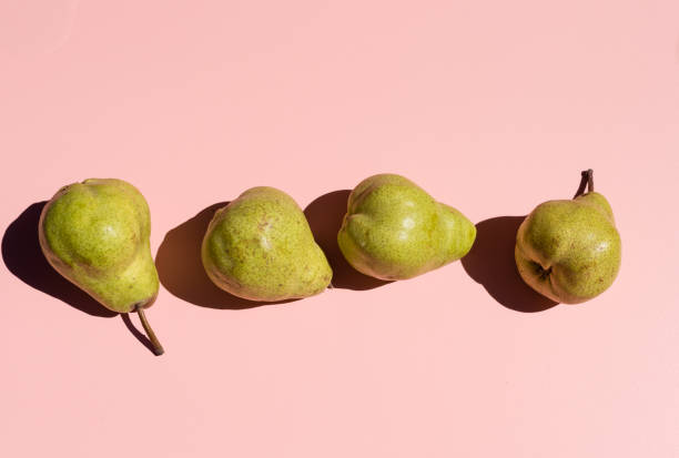 istock Green pears on pink with hard shadows 939341126