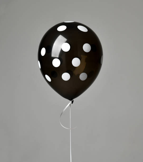 istock Single big black dotted latex balloon for birthday on a grey 939342784